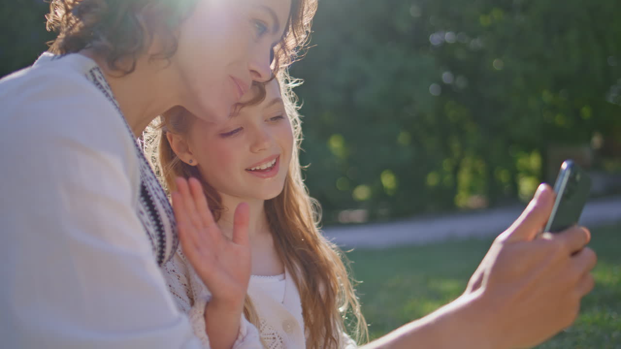 Mom kid talking cellphone sitting sunny nature closeup. Woman girl video calling