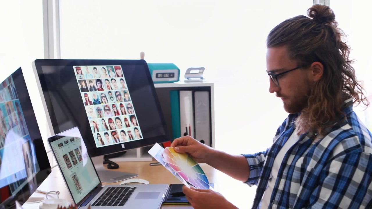 Animation of digital icons over caucasian male graphic designer holding color swatch at office