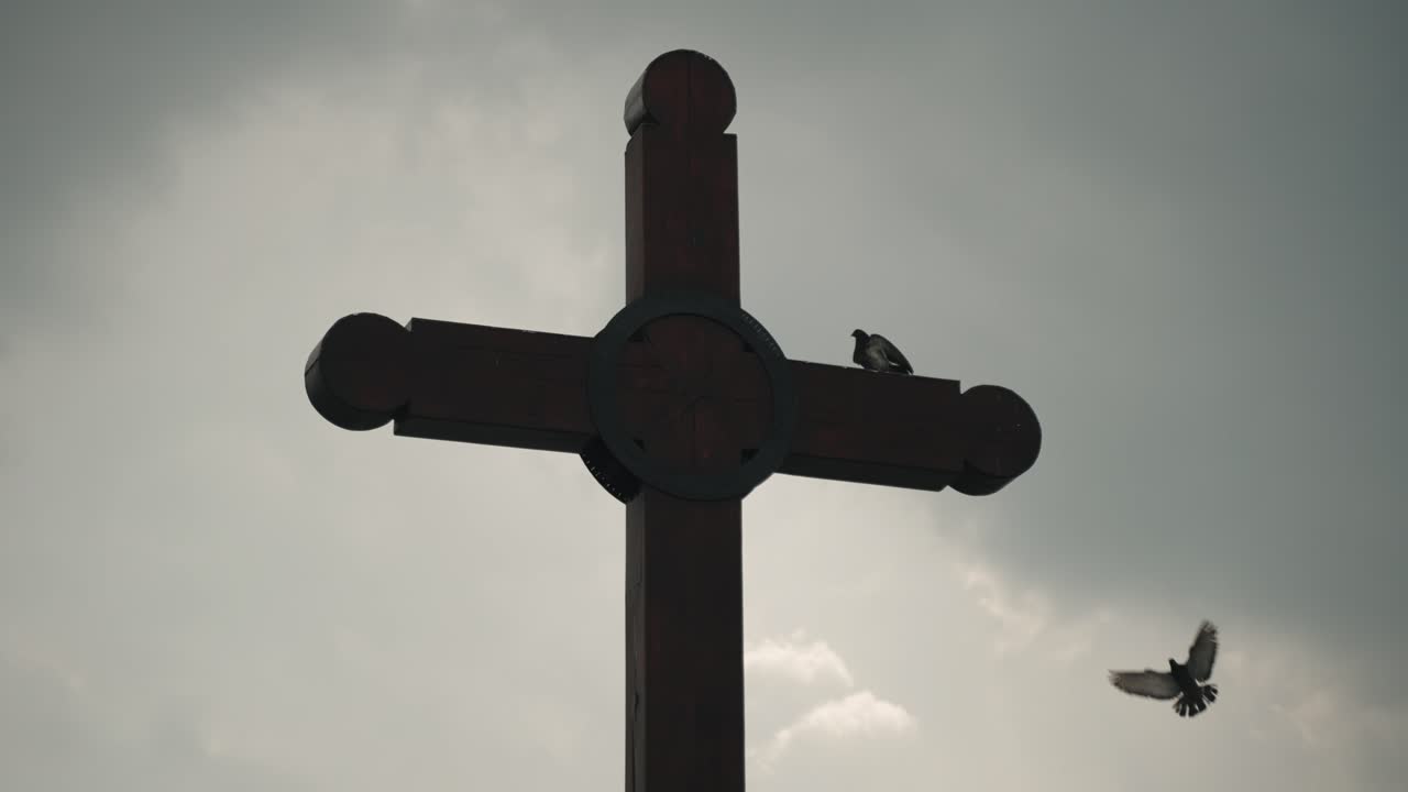 Silhouette Of Cross With Birds Flying And Perching Against Cloudy Sky Near Catedral de San Crist&oacute;bal de las Casas In Mexico