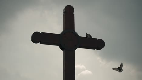 Silhouette-Eines-Kreuzes-Mit-Fliegenden-Und-Sitzenden-Vögeln-Vor-Bewölktem-Himmel-In-Der-Nähe-Der-Catedral-De-San-Cristóbal-De-Las-Casas-In-Mexiko