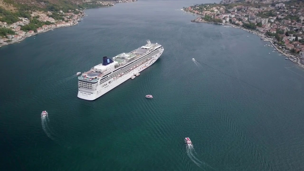 Krydstogtskib med tenderoperation i Kotor - Montenegro. Skibets tenderbåde og lokale både transporterer passagerer til udflugter