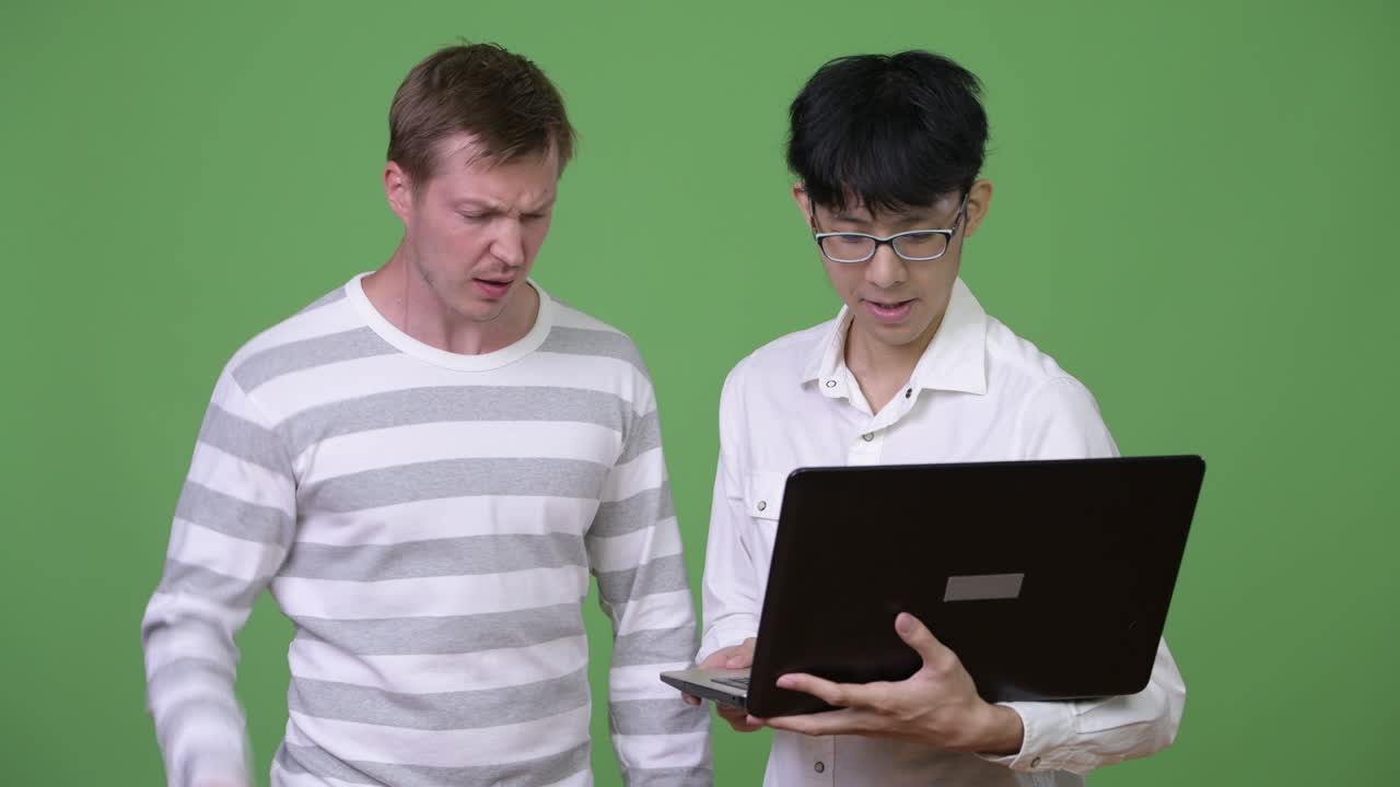 두 명의 슬픈 젊은 다민족 사업가들이 함께 나쁜 소식을 듣는 동안 노트북을 사용합니다.