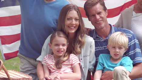 happy family smiling with an american flag in a park