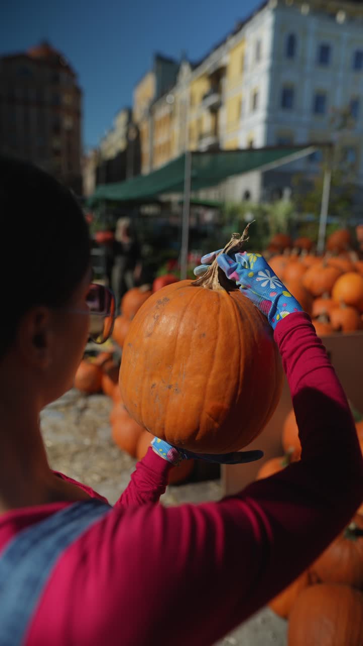 mujer recogiendo una calabaza en un mercado de otoño
