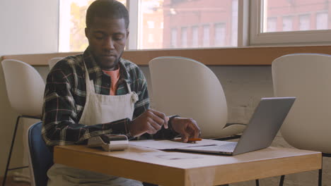 coffee shop owner sitting at table and calculating finance bill 1