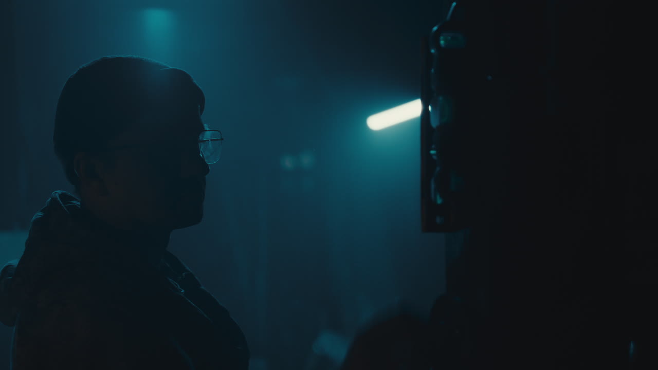 Mysterious man in the workshop at night smokes a cigarette