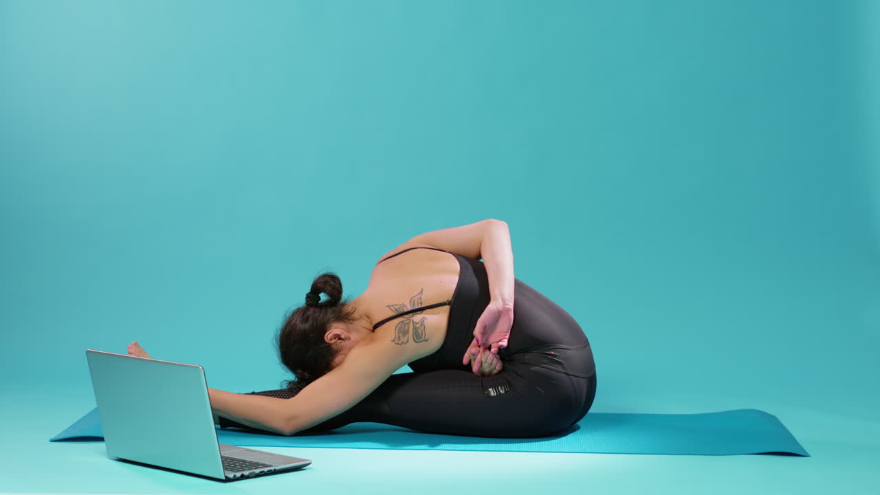 Fit woman doing stretching exercise and watching meditation video