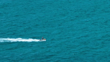 dynamic aerial video capturing a solo jet ski rider zipping across the expansive blue ocean