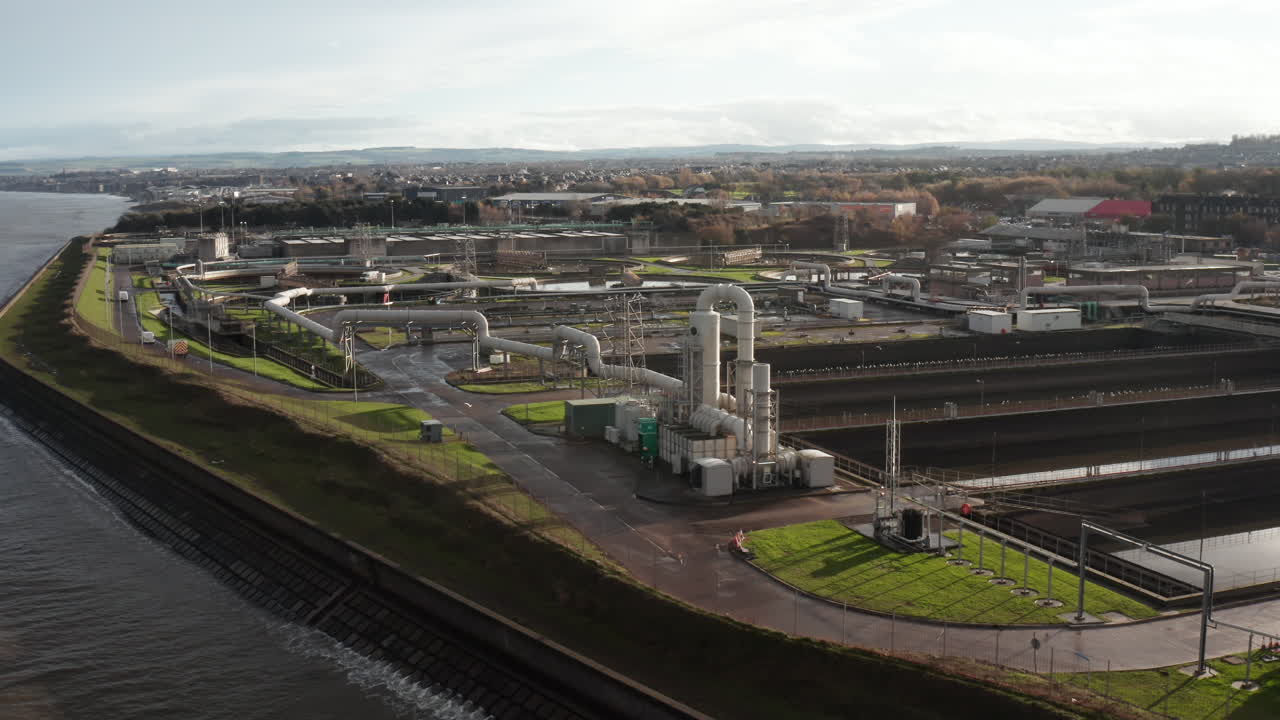 Aerial shot rising over a large sewage processing plant by the sea while birds fly by