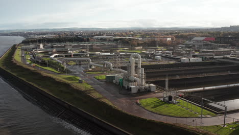 Aerial-shot-rising-over-a-large-sewage-processing-plant-by-the-sea-while-birds-fly-by