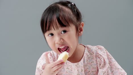 close up of little asian girl concentrate on food, smile and eat crispy butter toast happily at home