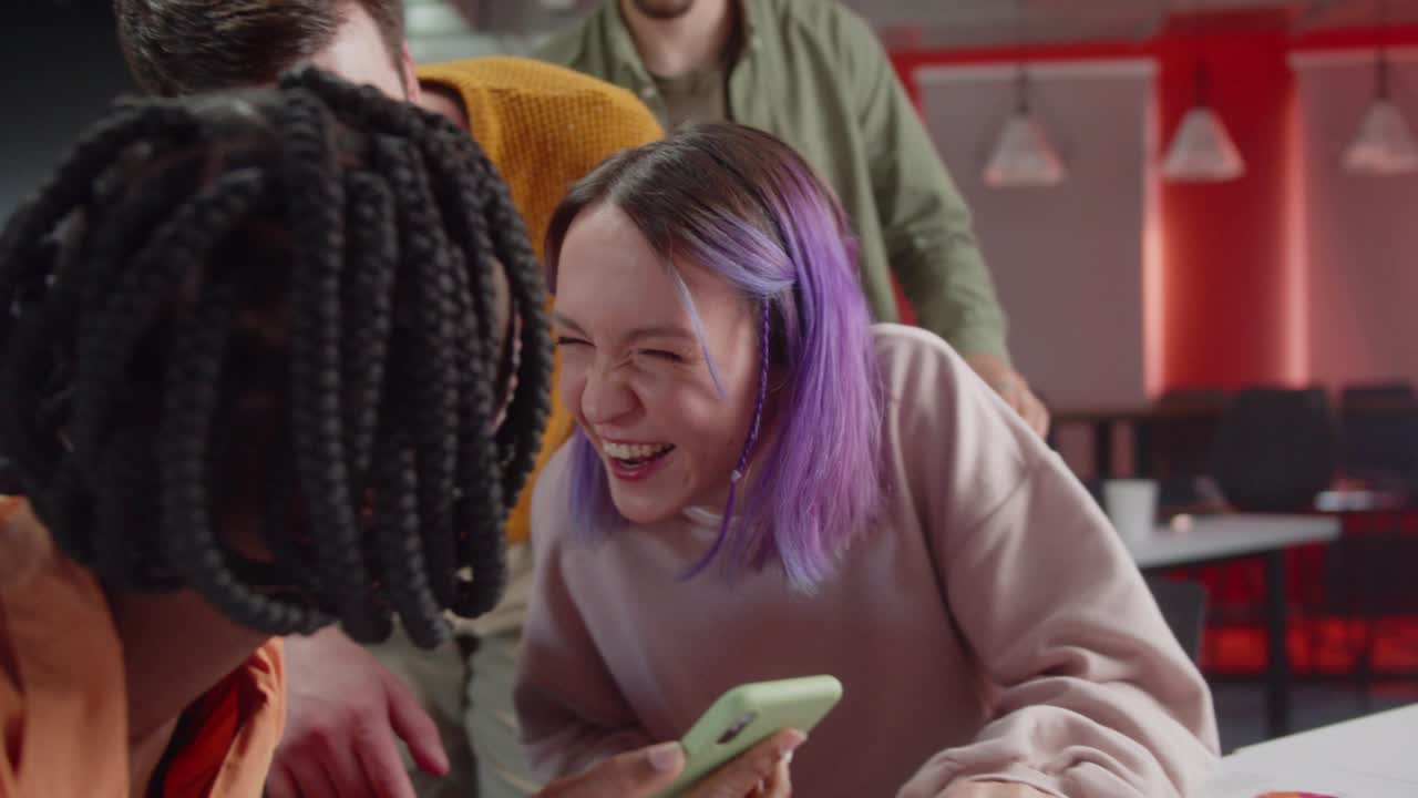 During breaking time, students are showing to their professor a funny video and they are laughing together, slow motion close up