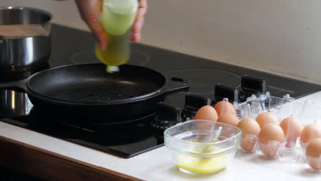 man puts oil in pan to cook eggs