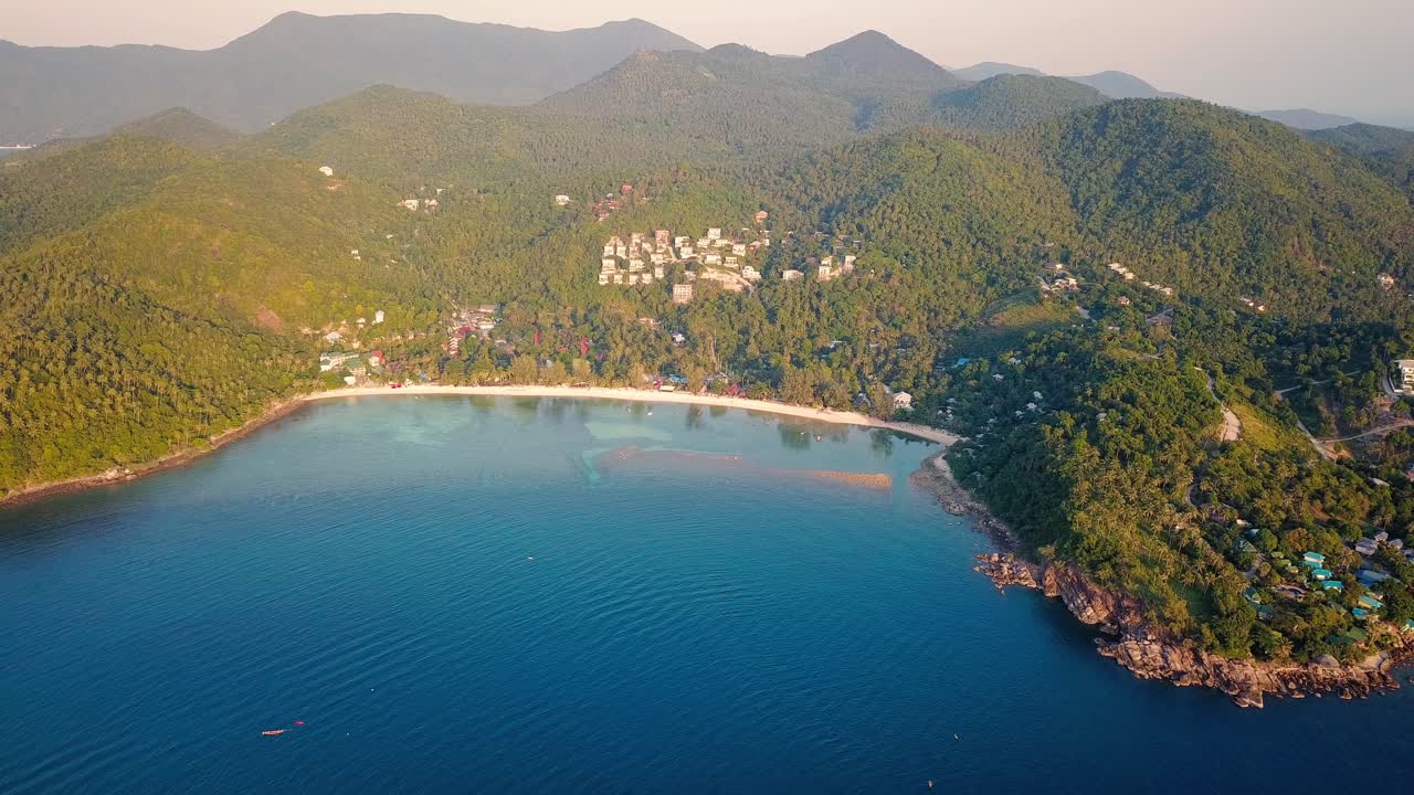 4k 공중 드론은 어선, 청록색 물, 산호 및 녹색 정글이 있는 태국 코팡안에 있는 샐러드 해변을 앞으로 밀어냅니다.