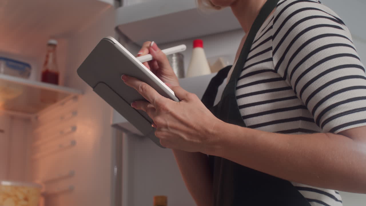 Woman Checking List of Ingredients Cooking at Kitchen