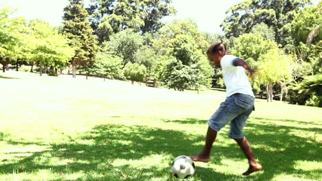 little boy playing football in the park