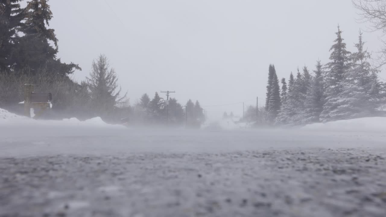 Snow dances on the concrete road during a snow storm blizzard