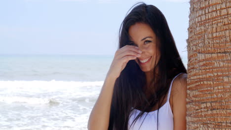 Mujer-Sonriente-En-La-Playa-Apoyada-Contra-El-árbol