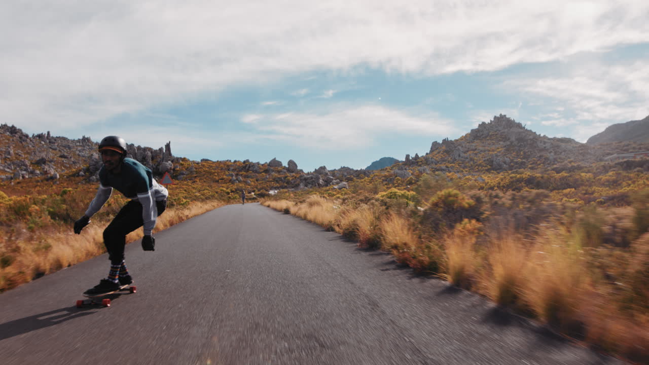 joven usando longboard patinaje rápido disfrutando del crucero cuesta abajo en una hermosa carretera de campo montando patinaje en cámara lenta