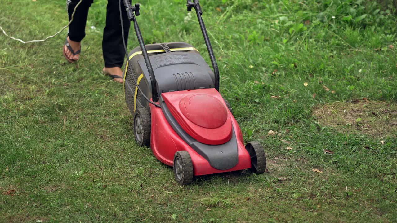 Woman cuts the lawn. Mowing lawns. Summer seasonal works in backyard.