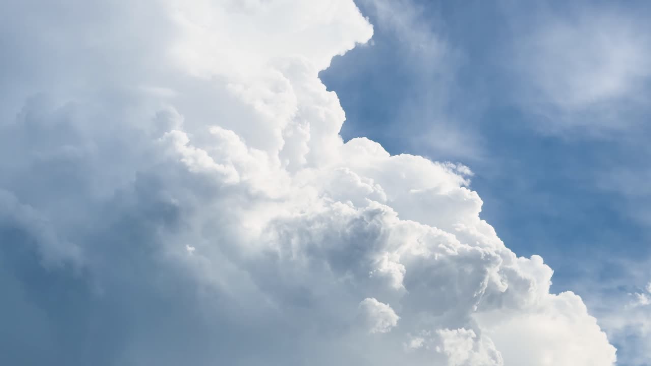 Dramatic cumulus clouds shift rapidly, sunlight filtering through, captured in smooth time-lapse motion