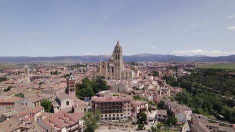 aerial view orbiting segovia roman catholic cathedral, plaza mayor scenic medieval cityscape and mountain skyline