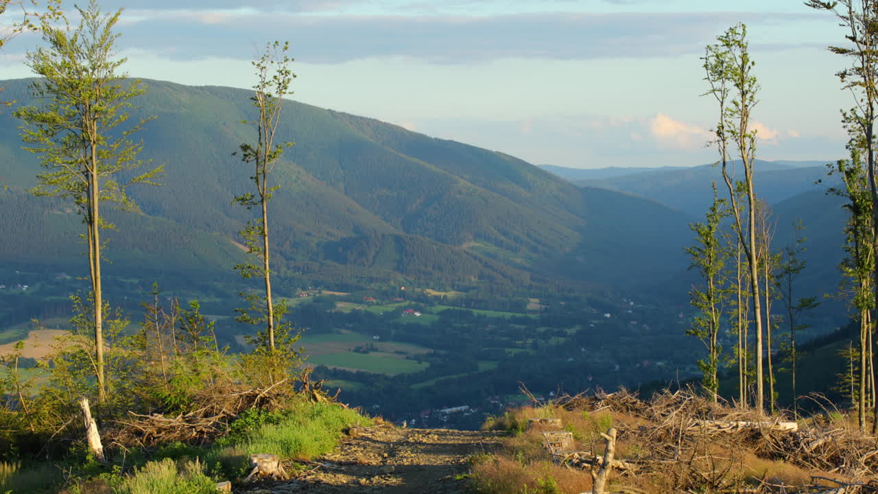 화창한 날 주변 언덕과 자연, 계곡에 있는 마을이 내려다보이는 산등성이로 이어지는 돌산길