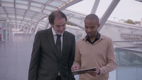 confident coworkers with tablet walking during meeting