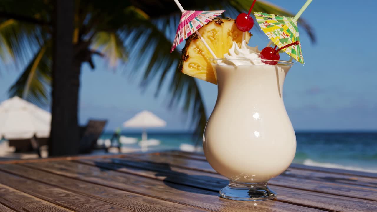 Tropical cocktail on a wooden table by the beach, shot from a low angle
