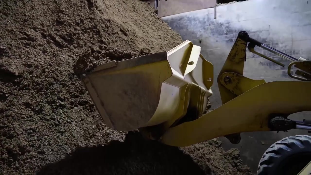 Front loader lifting a crushed clay mixture for roof tile production in a factory