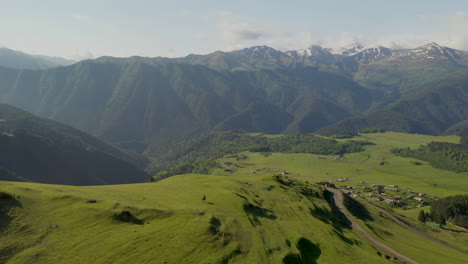 wide descending drone shot of man riding a horse in upper omalo, tusheti georgia