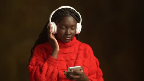 smiling african american teenager in headphones with smartphone