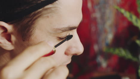 transgender man applying mascara to eyelashes