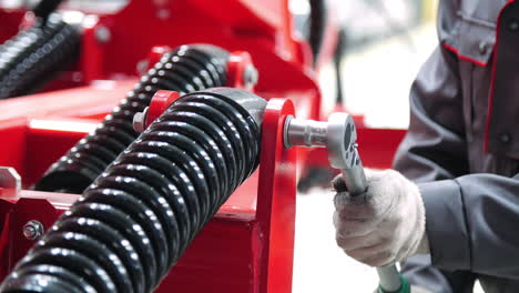 worker tightening nut on shock absorber of agricultural unit with socket wrench