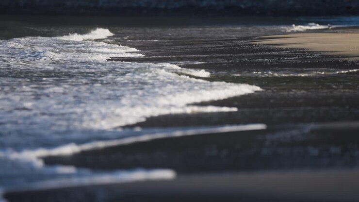 Waves roll slowly on the shallows of the sandy beach in Ersfjord