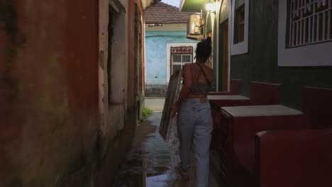 Muchacha-Joven-Que-Lleva-Una-Pintura-A-Través-De-Un-Callejón-Colorido-En-La-Tarde