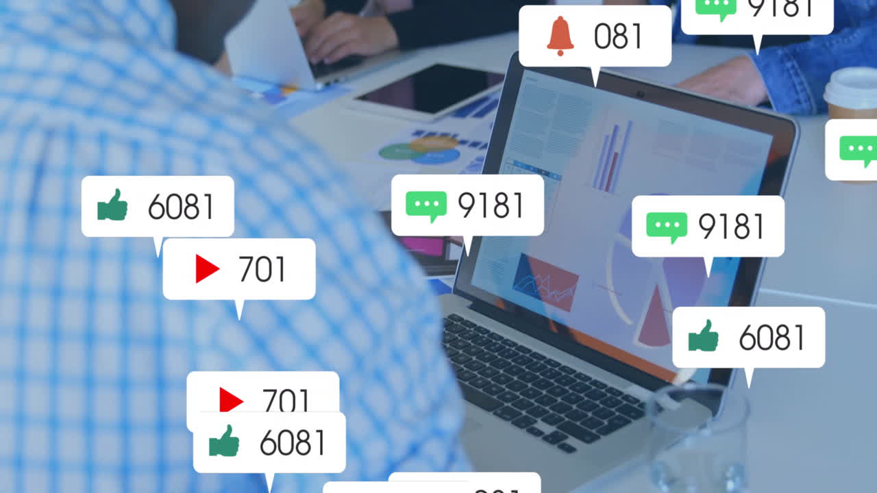 Team collaborating around conference table, reviewing business charts on laptop with overlay icons