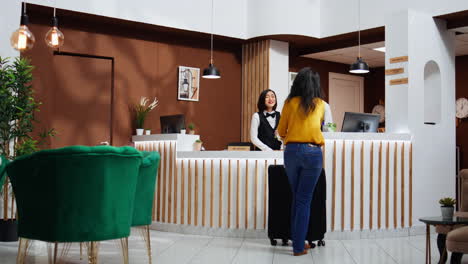 una mujer asiática se acerca a la recepción en el vestíbulo del hotel.
