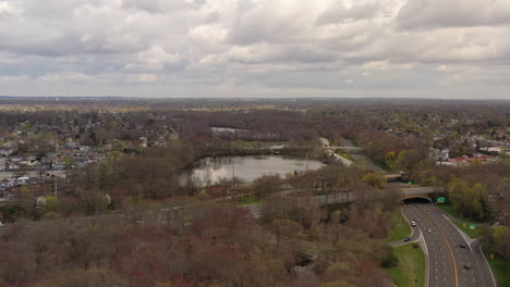 A-drone-view-over-a-lake,-surrounded-by-dry-trees-and-paved-roads