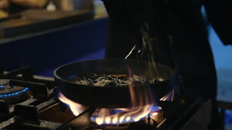 cocinero profesional que añade queso rallado a los fideos