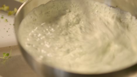 whisking ingredients in a metal bowl to create a creamy mixture, panning close-up