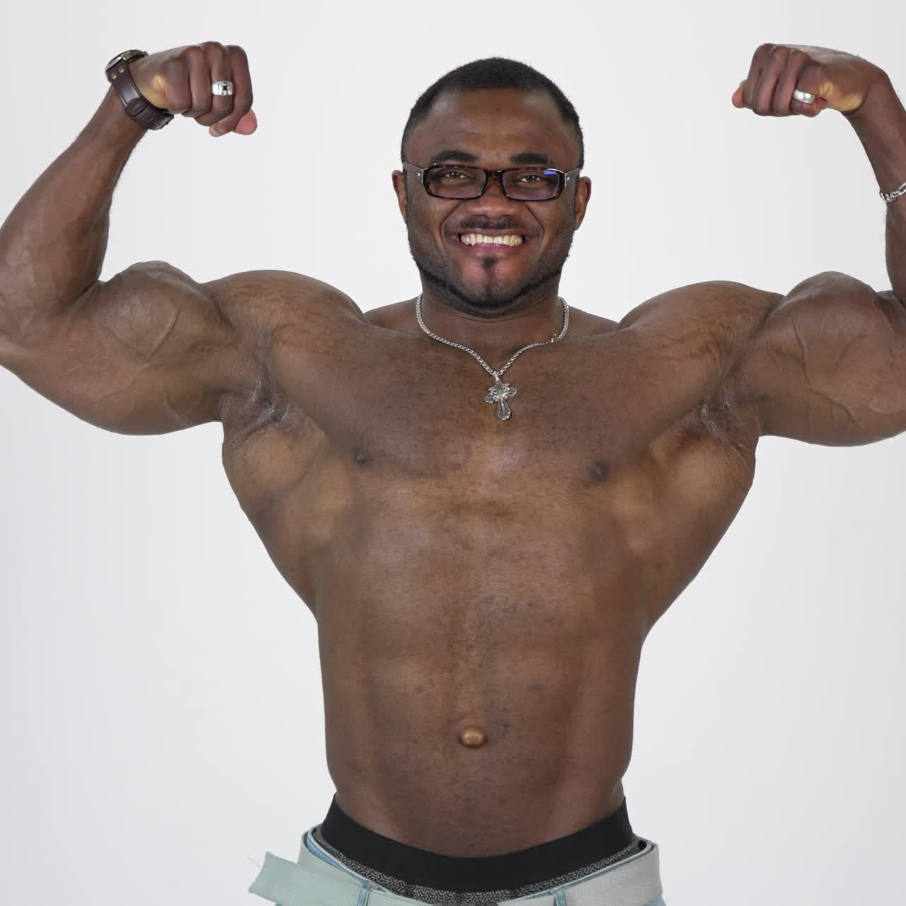 Portrait of athletic african man. Smiling shirtless sportsman with black skin with stretched his arms to the sides and showing his large muscles on white background