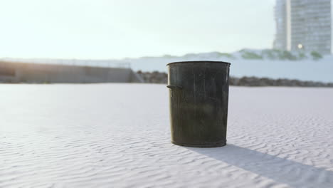 Gray-metal-garbage-bin-or-trash-can-on-the-beach