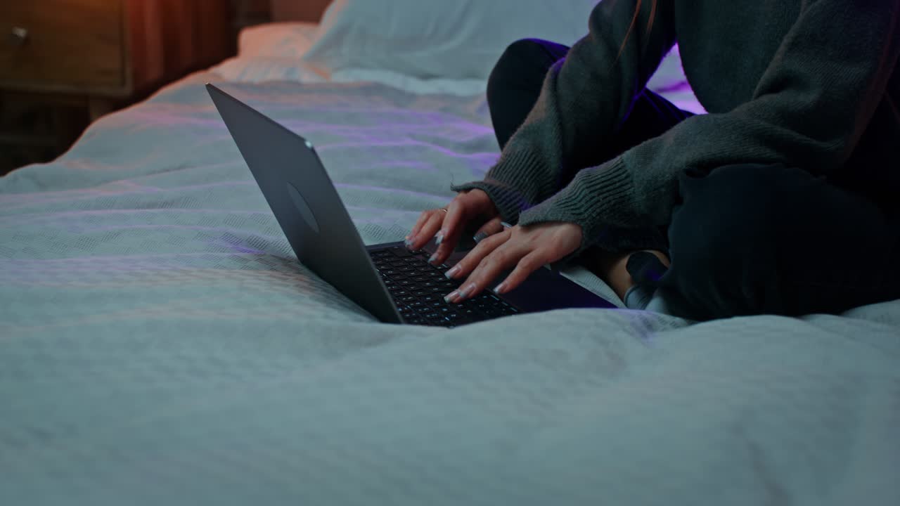 mujer trabajando en una computadora portátil en su cama por la noche