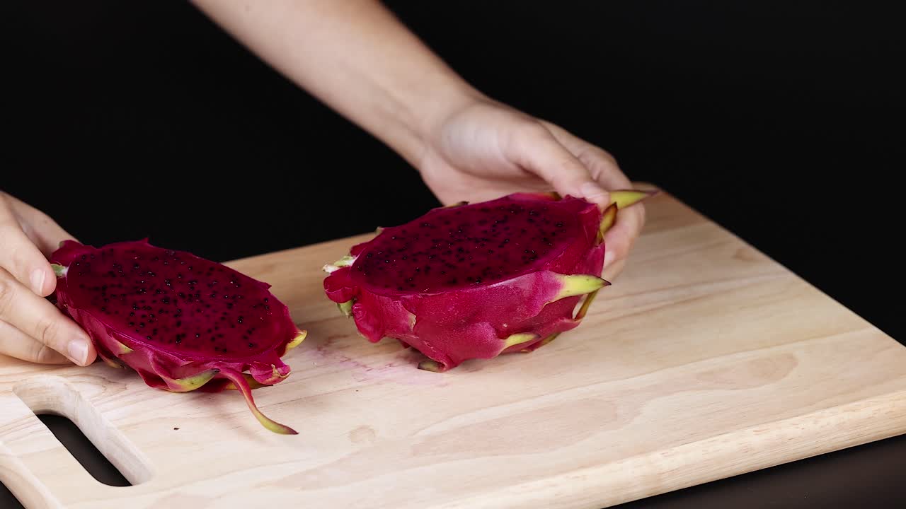 Hands cutting and displaying dragon fruit halves