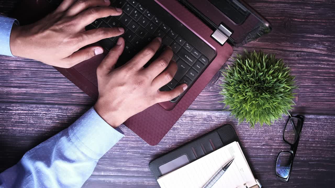 Person Typing on a Laptop at a Wooden Desk