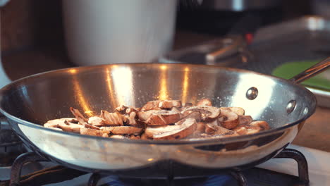 Sprinkling-salt-over-sliced-fresh-mushrooms-steaming-and-simmering-in-a-skillet-on-the-stove---isolated