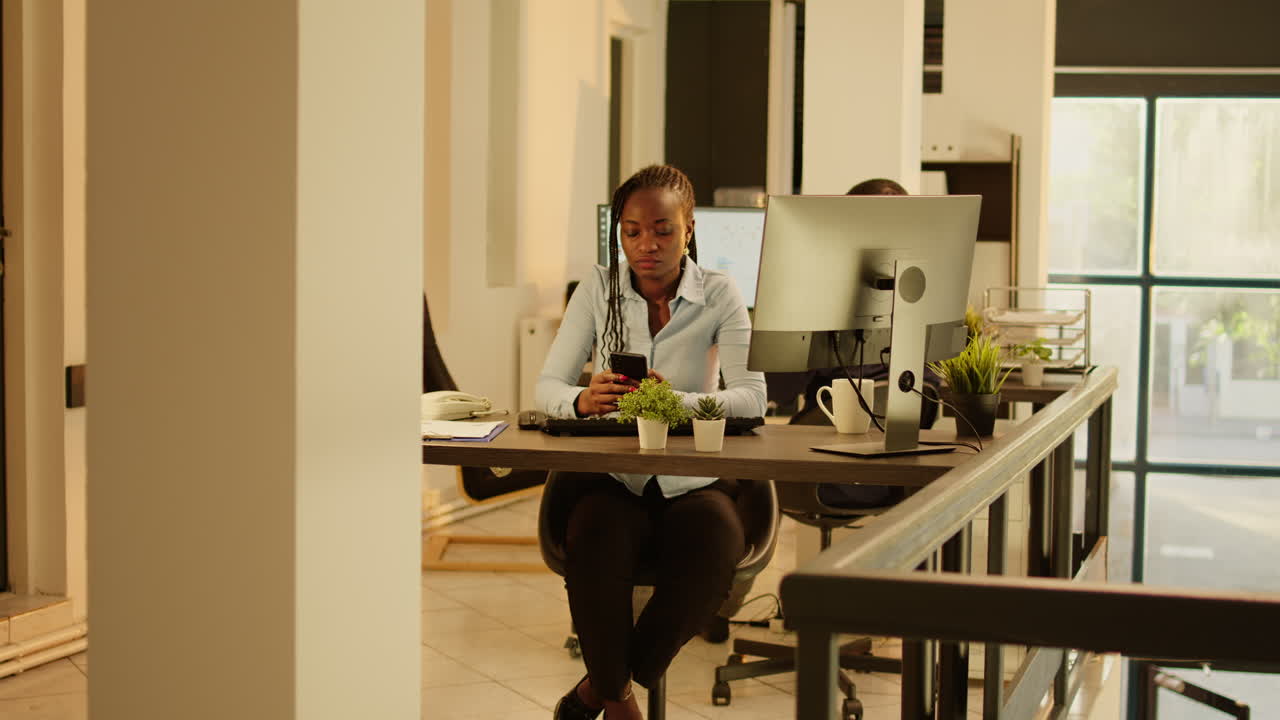 Woman working at a desk with computer and phone