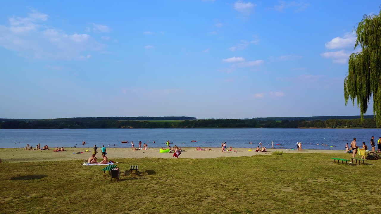 Lake Beach Scene with People Relaxing and Swimming