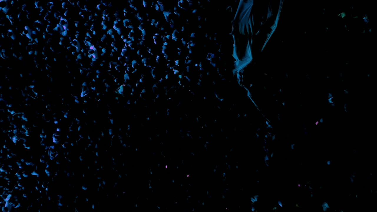 무대 푸른 불빛으로 조명 된 드론과 함께 콘서트 또는 축제에 참석하는 사람들의 군중의 놀라운 느린 동작 영화 상공